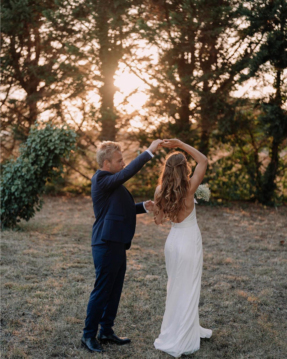 Couple dancing in a field, woman wearing a sleek white sleeveless slip dress.