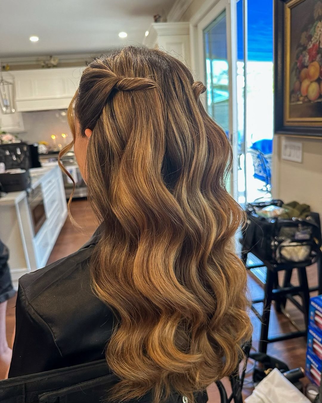 Long wavy light brown hair with blonde highlights styled in a half-up hairstyle.