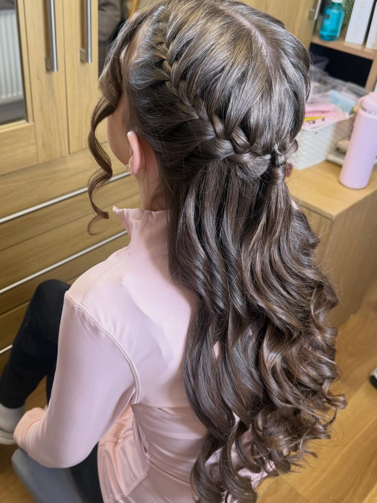 Long wavy brown hair styled with thick side braids in a half-up, half-down fashion.