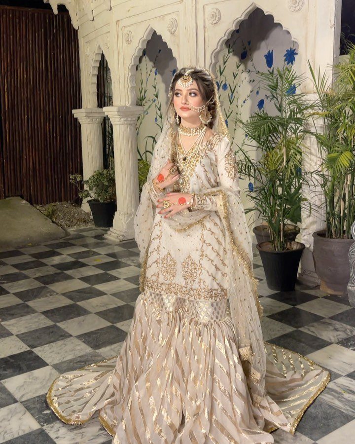 Woman in a cream and gold embroidered bridal dress with a matching dupatta.