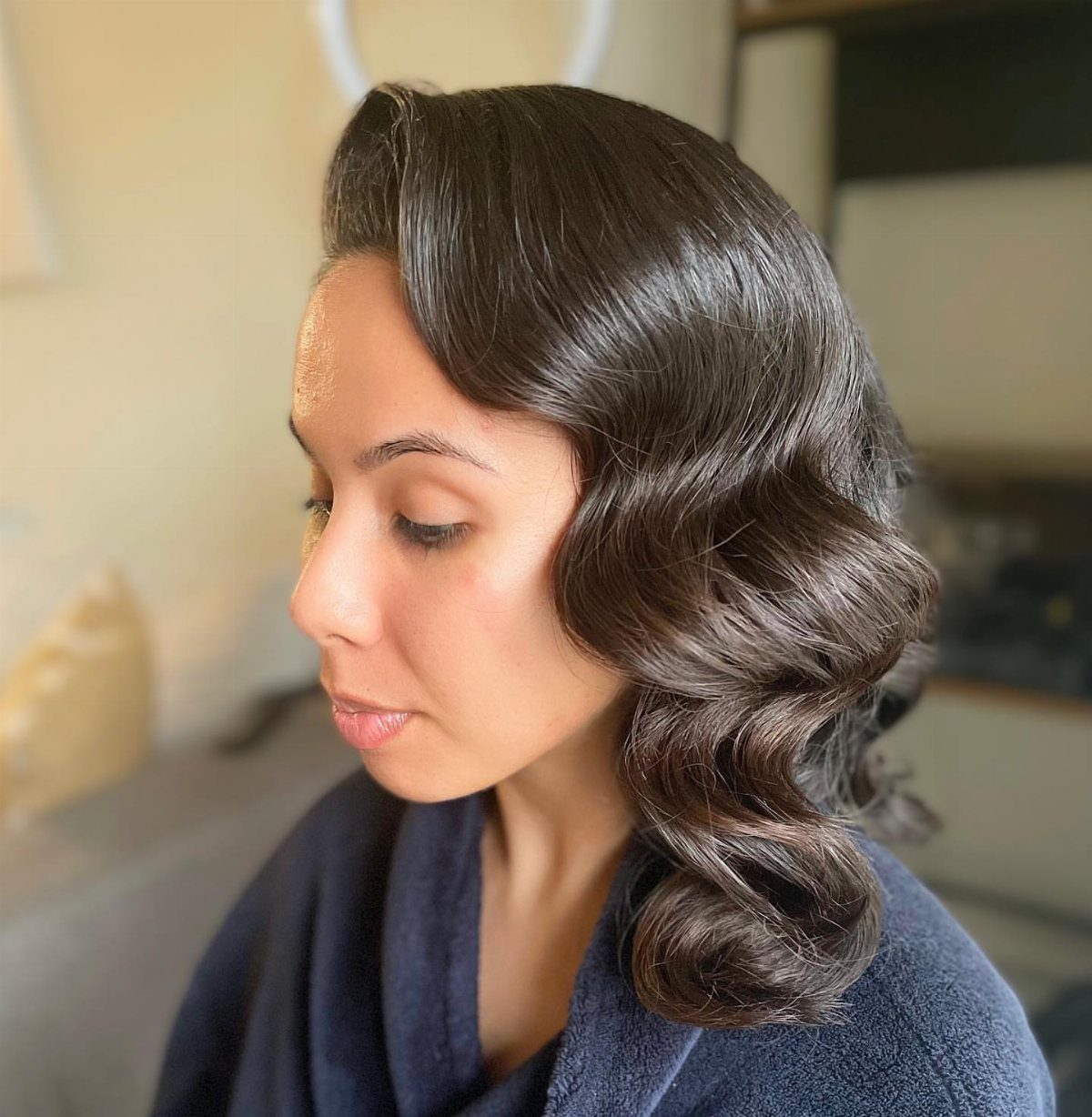 Woman with dark brown hair styled in polished, vintage Hollywood waves.