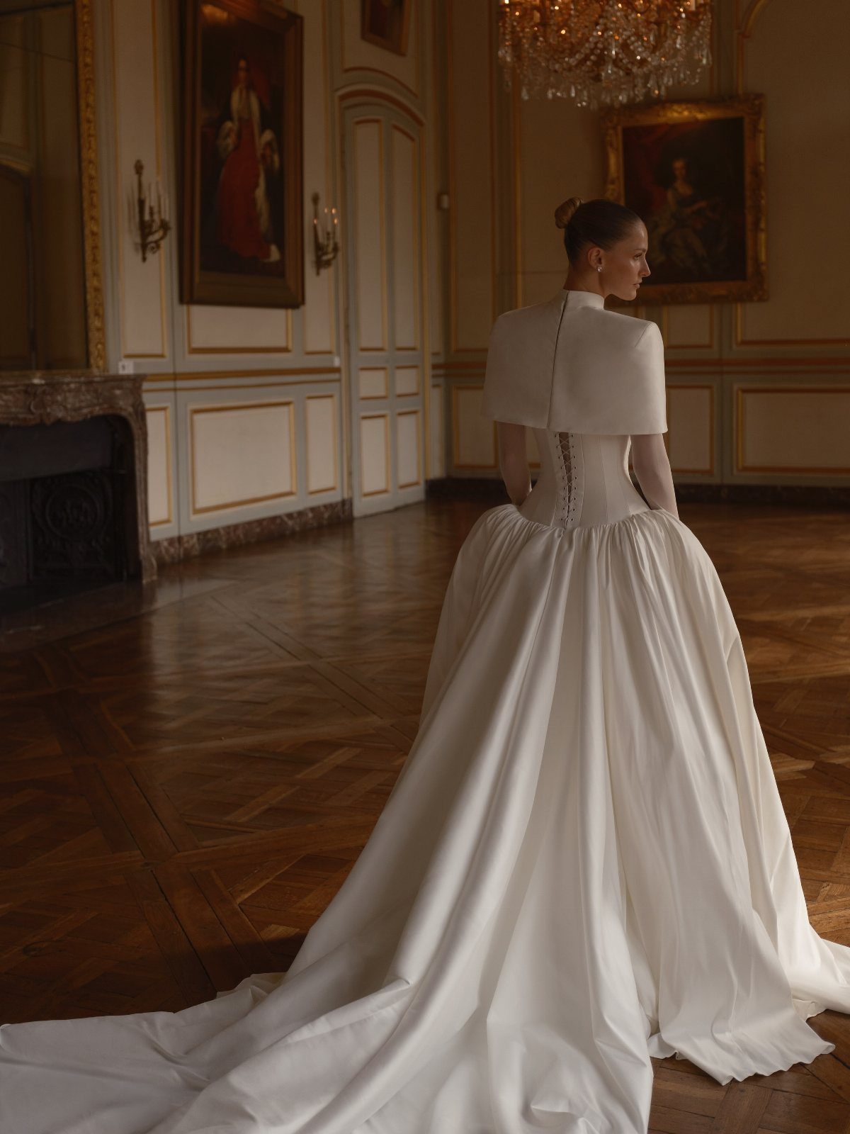 Woman in a white vintage wedding dress with a capelet in an elegant room