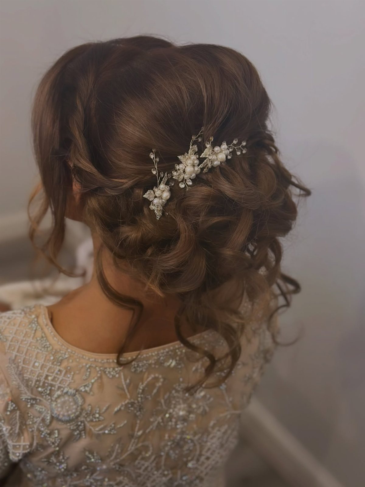 A woman's brown hair styled in a textured updo with a floral hair accessory.